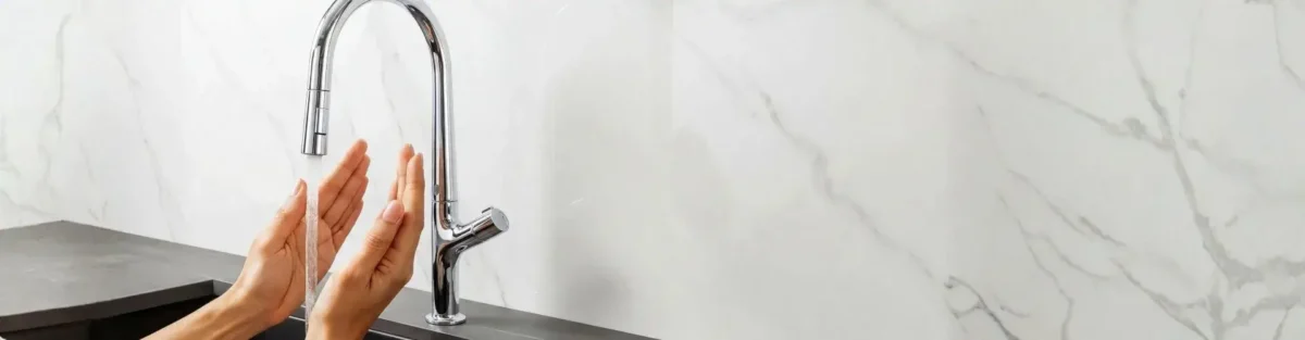 Usuario usando griferías electrónicas en su hogar.